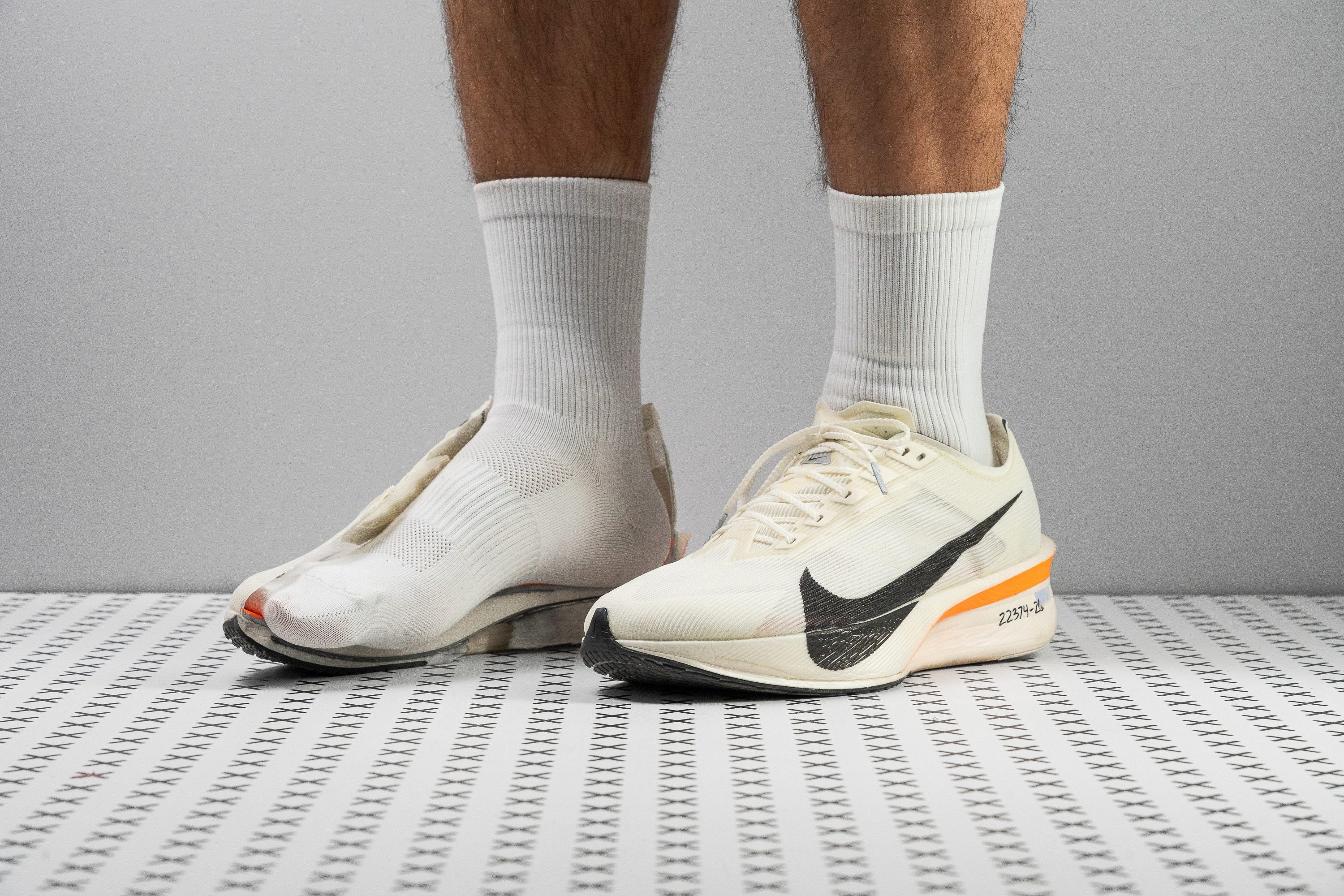 Sleek carbon-plated racing shoe on a dark surface with dramatic spotlight